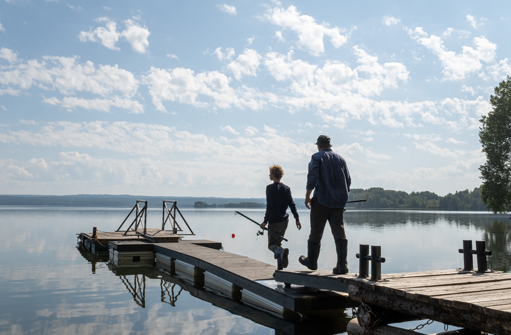 Father and son walking with fishing gear towards a lake
